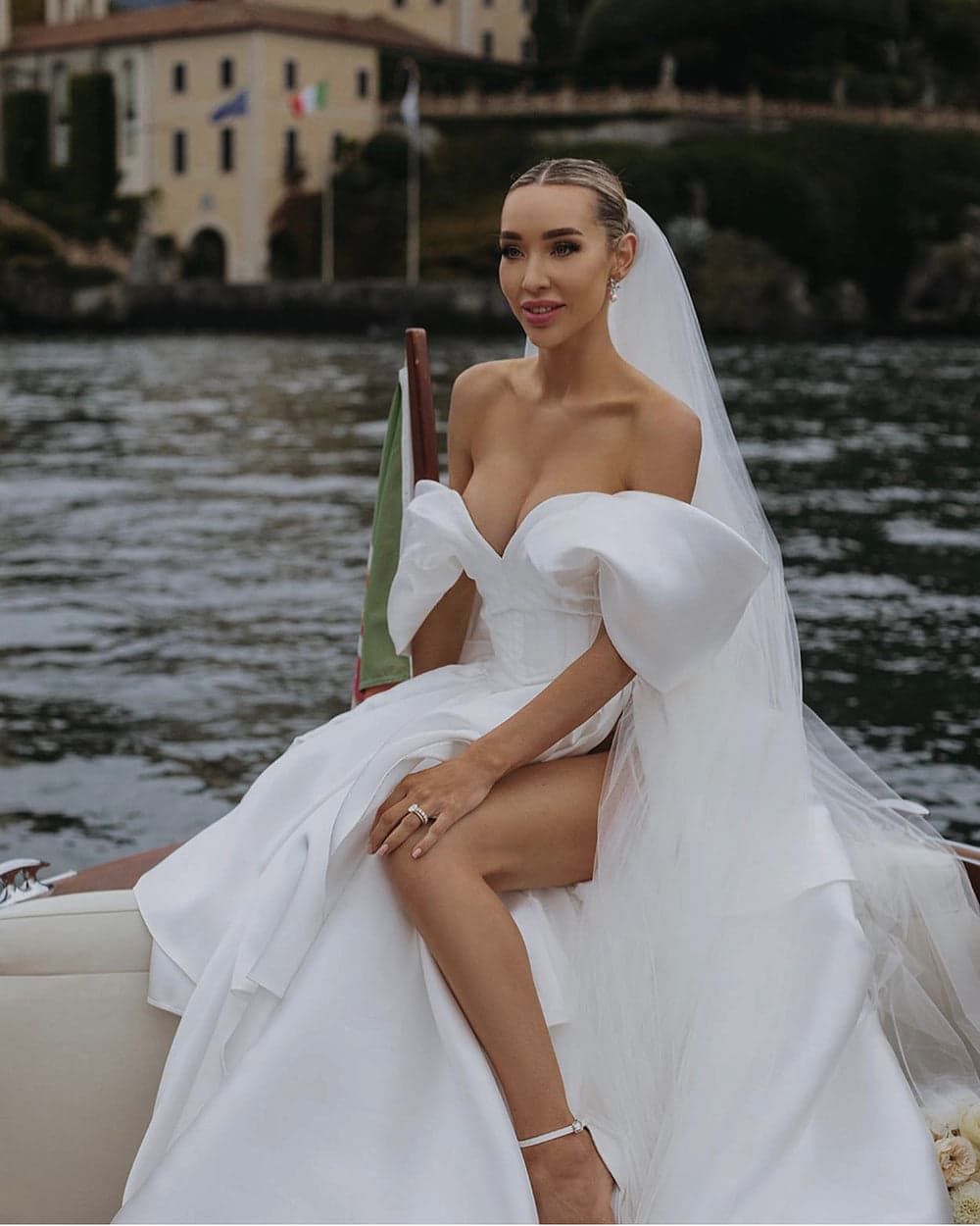 An ivory off-the-shoulder bridal look with a veil, pictured on a boat in the Khirzad collection.